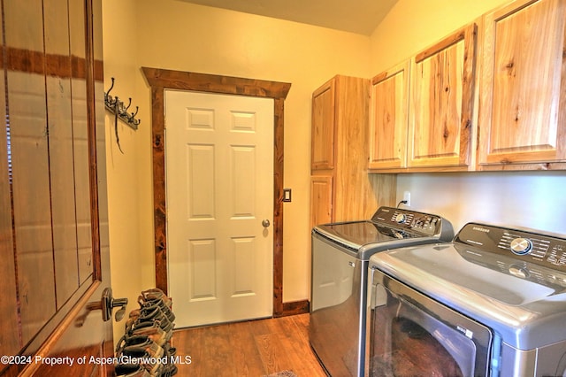 washroom with dark hardwood / wood-style flooring, cabinets, and washing machine and dryer