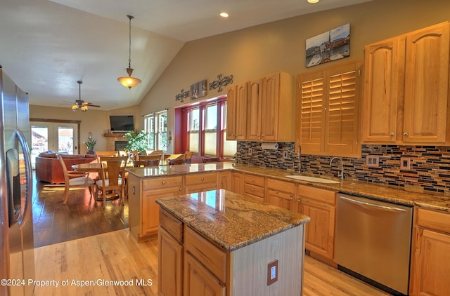 kitchen featuring appliances with stainless steel finishes, vaulted ceiling, sink, decorative light fixtures, and a center island