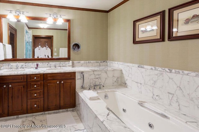 bathroom with crown molding, a sink, a jetted tub, and double vanity