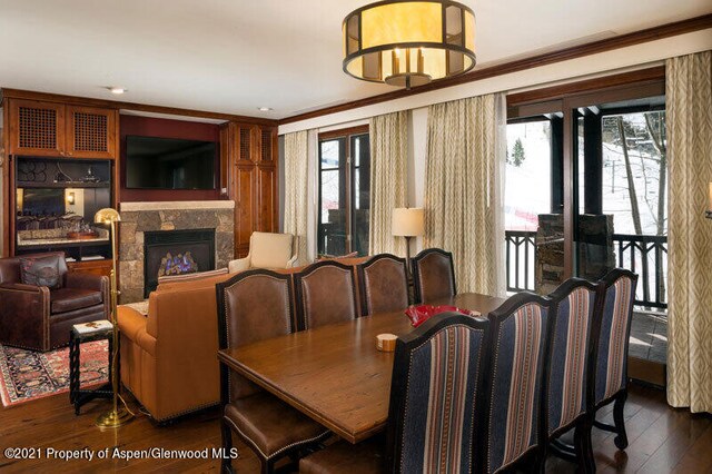 dining room featuring a fireplace, dark wood-type flooring, and crown molding