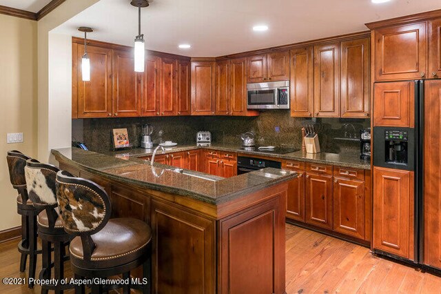 kitchen featuring tasteful backsplash, stainless steel microwave, paneled built in refrigerator, black electric cooktop, and a sink