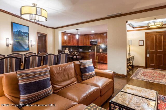 living room with visible vents, crown molding, baseboards, and hardwood / wood-style flooring