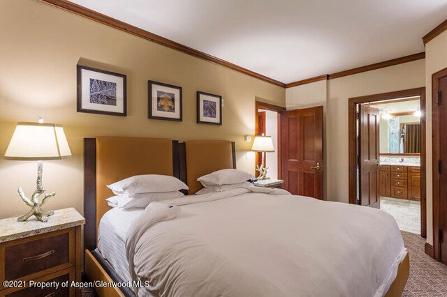 carpeted bedroom with crown molding and ensuite bathroom