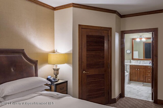 carpeted bedroom with ornamental molding, baseboards, and ensuite bathroom