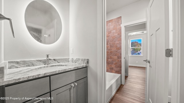 bathroom featuring vanity, brick wall, and wood finished floors