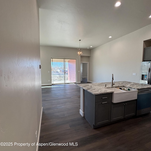 kitchen with open floor plan, decorative light fixtures, light stone countertops, stainless steel appliances, and a sink