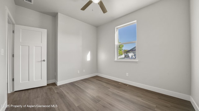 unfurnished bedroom featuring a ceiling fan, visible vents, baseboards, and wood finished floors