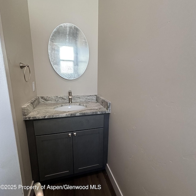 bathroom with wood finished floors, vanity, and baseboards