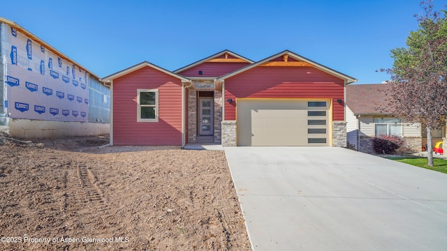 view of front of property with driveway, stone siding, and an attached garage