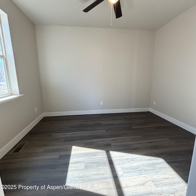 spare room with visible vents, dark wood finished floors, and baseboards