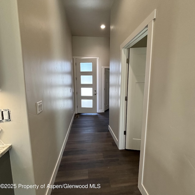 hallway featuring dark wood finished floors and baseboards