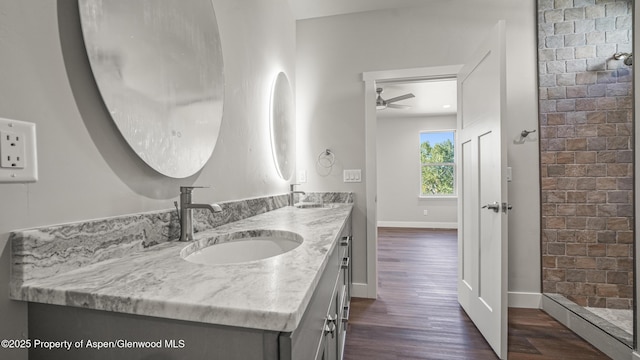 bathroom with double vanity, wood finished floors, a sink, and baseboards