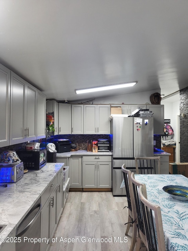 kitchen with gray cabinetry, decorative backsplash, light hardwood / wood-style flooring, and appliances with stainless steel finishes