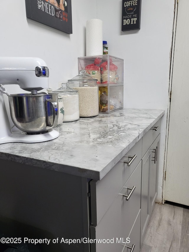 interior space with gray cabinets, light stone countertops, and light hardwood / wood-style flooring