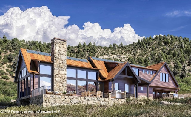 902/904 Sopris Creek Rd, Basalt, CO 81621 - back of property featuring a standing seam roof, solar panels, stone siding, a metal roof, and a chimney