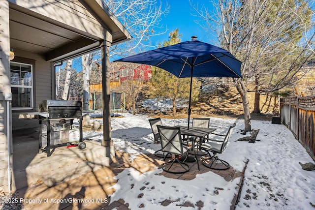 snow covered patio featuring area for grilling and a trampoline