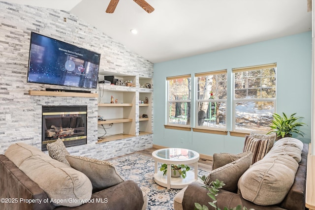 living room with lofted ceiling, a stone fireplace, ceiling fan, wood-type flooring, and built in shelves