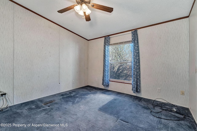 carpeted empty room with ornamental molding, visible vents, ceiling fan, and a textured ceiling
