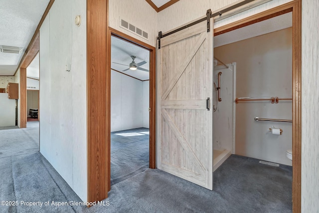 hall featuring a barn door, carpet floors, and visible vents