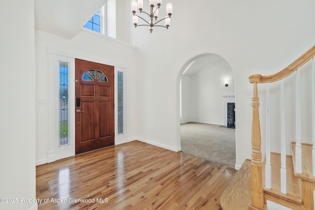 1020 Alta Vista Dr, Craig, CO 81625 - foyer entrance featuring light wood-style flooring, arched walkways, a chandelier, a high ceiling, and a fireplace