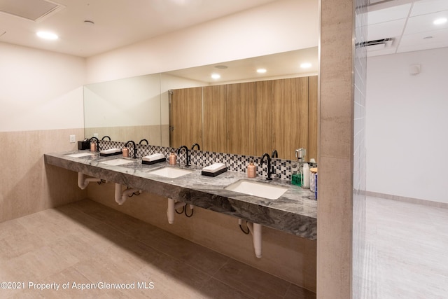 bathroom with recessed lighting, tile walls, and double sink