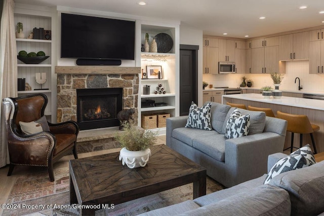living room featuring recessed lighting, a stone fireplace, and wood finished floors