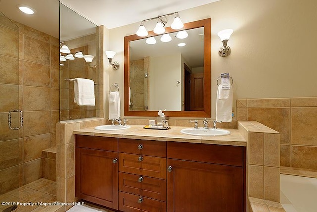 bathroom with a sink, a bathing tub, a shower stall, and double vanity