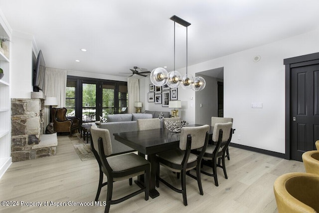 dining space featuring light wood-style floors, crown molding, a fireplace, and a ceiling fan