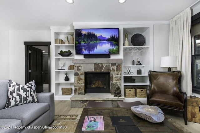 living room with recessed lighting, a fireplace, built in features, and wood finished floors