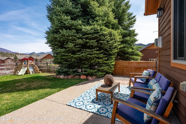 view of patio featuring fence, a mountain view, a playground, and an outdoor hangout area