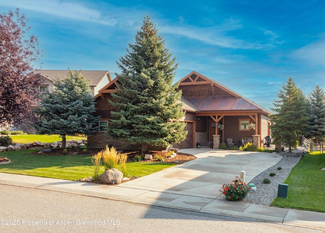 view of front facade with a front yard, an attached garage, stone siding, metal roof, and concrete driveway