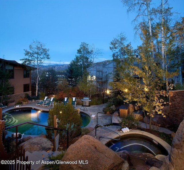 pool with a patio area and an in ground hot tub