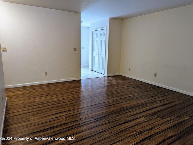 unfurnished room with dark wood-type flooring