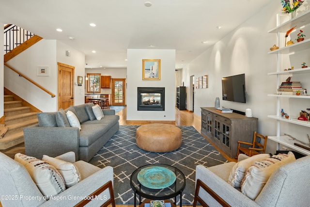 living area with recessed lighting, stairway, wood finished floors, and a multi sided fireplace