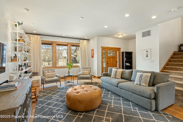 living room featuring recessed lighting, wood finished floors, visible vents, baseboards, and stairway