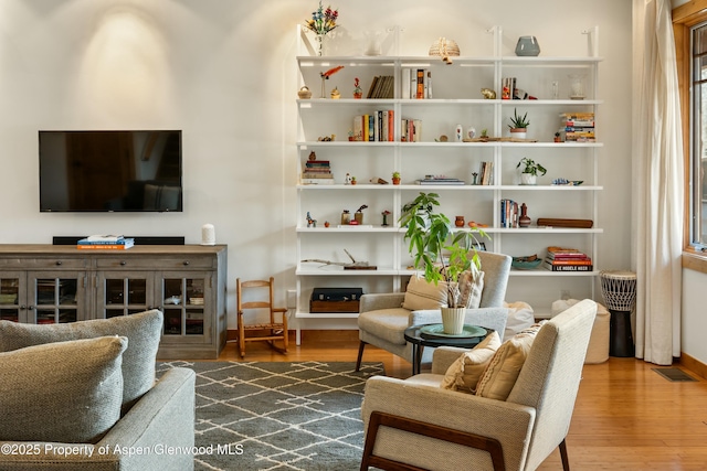 sitting room featuring wood finished floors, visible vents, and baseboards