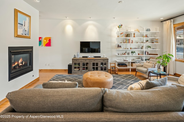 living room with a glass covered fireplace, recessed lighting, and wood finished floors