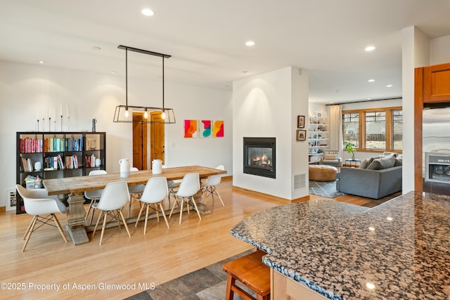 dining area with baseboards, a fireplace, light wood-style flooring, and recessed lighting