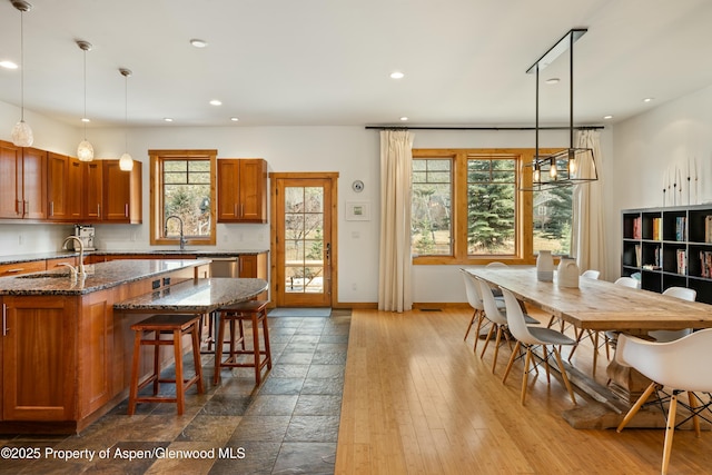 kitchen with brown cabinets, a sink, and dark stone countertops