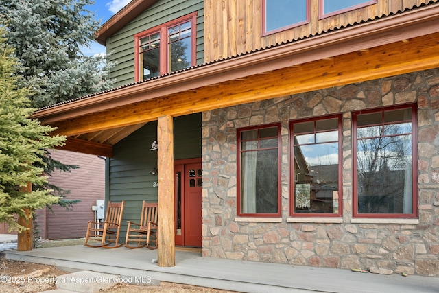 view of exterior entry featuring board and batten siding and covered porch