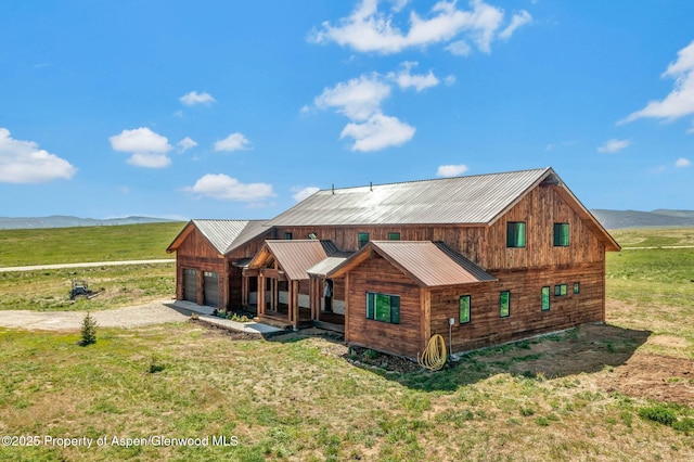 rear view of house with a yard, a rural view, a mountain view, and an attached garage