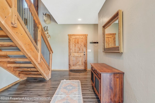 foyer featuring stairs, dark wood-style flooring, and baseboards