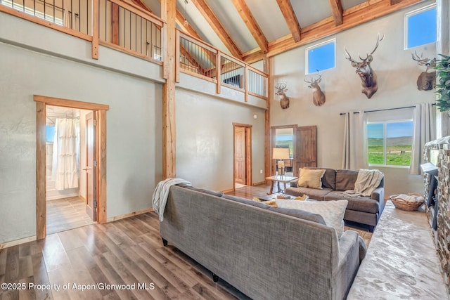 living area with high vaulted ceiling, beamed ceiling, baseboards, and wood finished floors