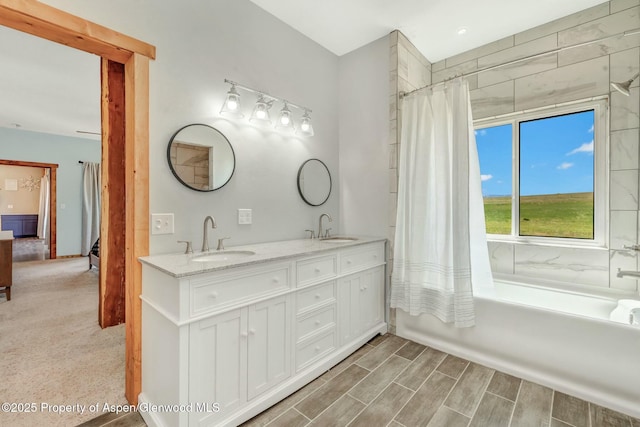 bathroom with ensuite bathroom, double vanity, a sink, and shower / bath combo with shower curtain