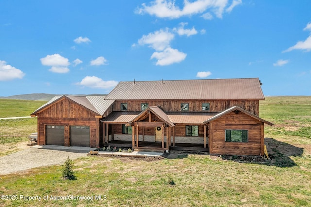 view of front of property with a garage, metal roof, gravel driveway, a mountain view, and a porch