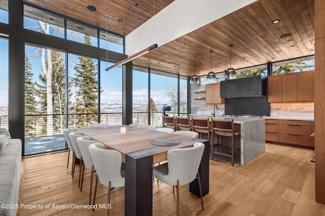 dining space with floor to ceiling windows, wood ceiling, and light wood-type flooring