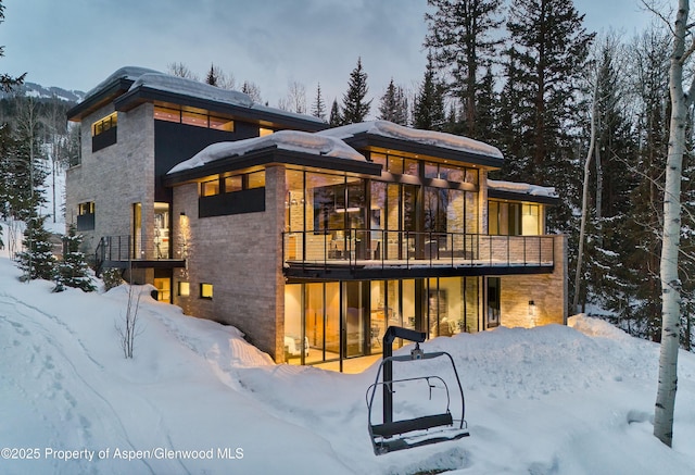 snow covered back of property featuring a balcony