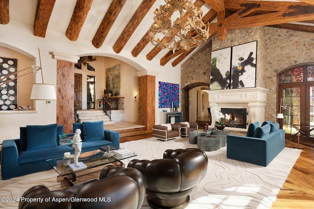 120 Running Mare Rd, Woody Creek, CO 81656 - living area with arched walkways, beamed ceiling, wood finished floors, a premium fireplace, and a chandelier