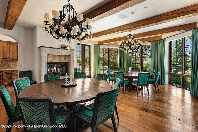 120 Running Mare Rd, Woody Creek, CO 81656 - dining space featuring a chandelier, beam ceiling, wood-type flooring, a glass covered fireplace, and arched walkways