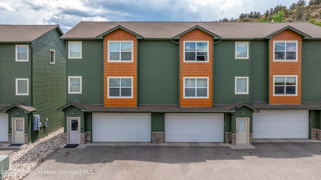 2433 Pine Ln, Rifle, CO 81650 - townhome / multi-family property with a garage, stone siding, and roof with shingles